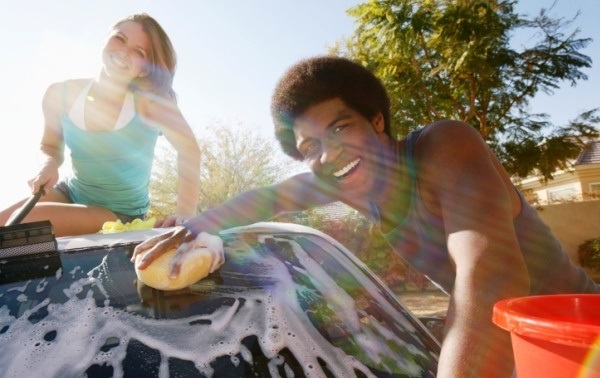 Young couple washing car outdoors, portrait