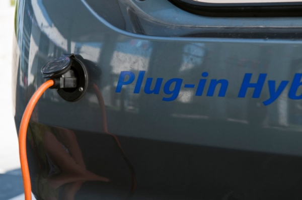 Close up of electrical plug recharging electric car